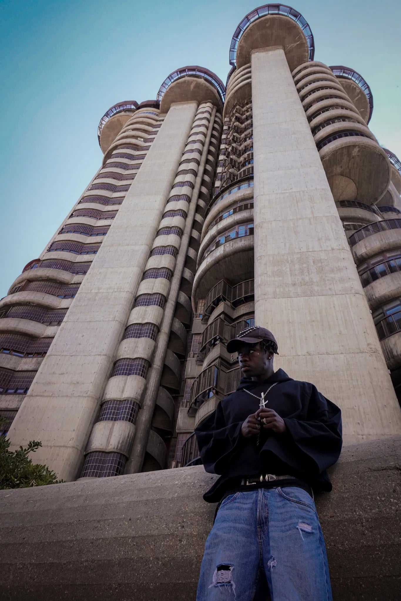 Vista en contrapicado de un edificio brutalista detrás de modelo durante la Sesión Drop 02