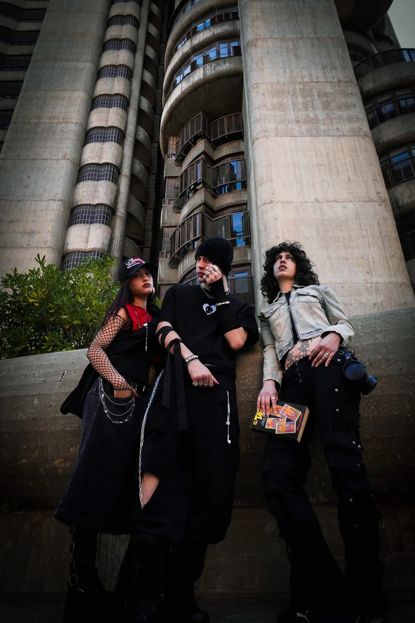 Tres miembros de Skull Hearts posando juntos frente a un edificio de hormigón en estilo urbano y rebelde